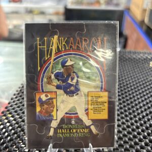 Hank Aaron Donruss Hall of Fame Diamond King puzzle card, vintage baseball collectible featuring legendary slugger stats in protective display sleeve, rare nine-piece sports trading card masterpiece for serious baseball fans.