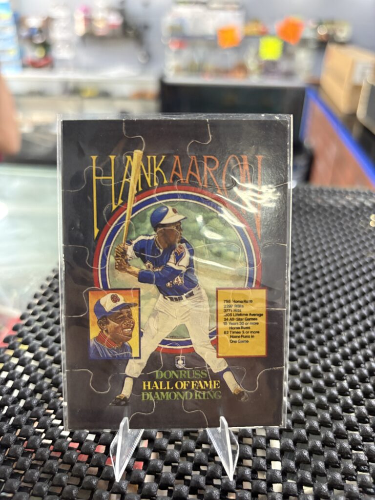 Hank Aaron Donruss Hall of Fame Diamond King puzzle card, vintage baseball collectible featuring legendary slugger stats in protective display sleeve, rare nine-piece sports trading card masterpiece for serious baseball fans.