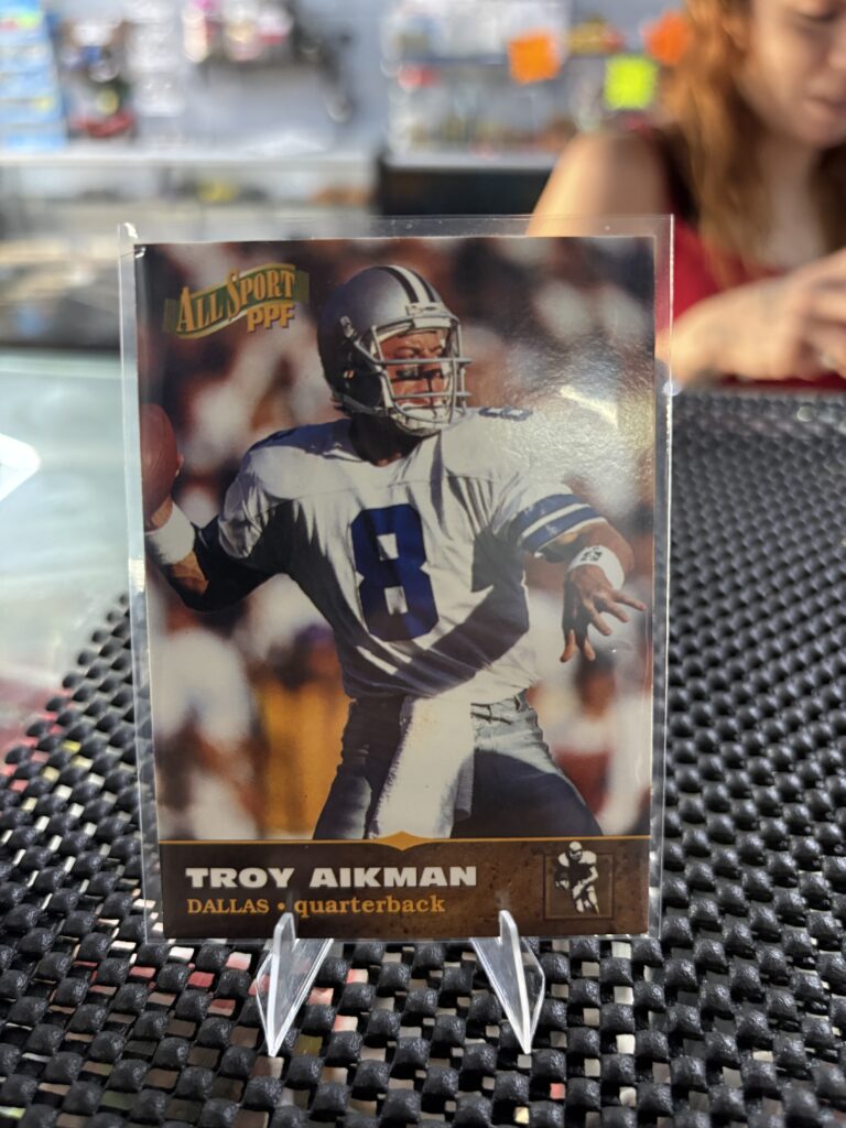 Dallas Cowboys Troy Aikman 1996 All Sport PPF football trading card, action shot in protective sleeve, high quality vintage NFL quarterback collectible in a clear display case for serious sports fans.