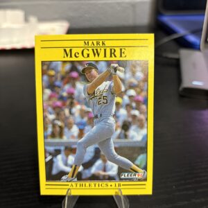 Oakland Athletics Mark McGwire 1991 Fleer baseball trading card, powerful swinging action shot in protective sleeve, high quality vintage rare collectible in clear display case for serious baseball fans and investors today.
