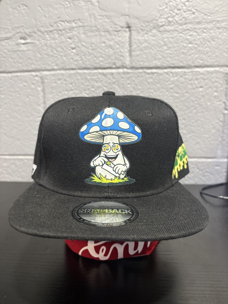 Black snapback cap featuring a vibrant, stylized mushroom character graphic, a bold and eccentric accessory for collectors looking to add high-energy, unique assets to their portfolio today.