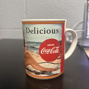 1987 vintage Coca-Cola "Through The Years: 1950" ceramic mug featuring classic pin-up style beach illustration, a nostalgic and highly collectible piece of breweriana for enthusiasts building a high-value portfolio today.