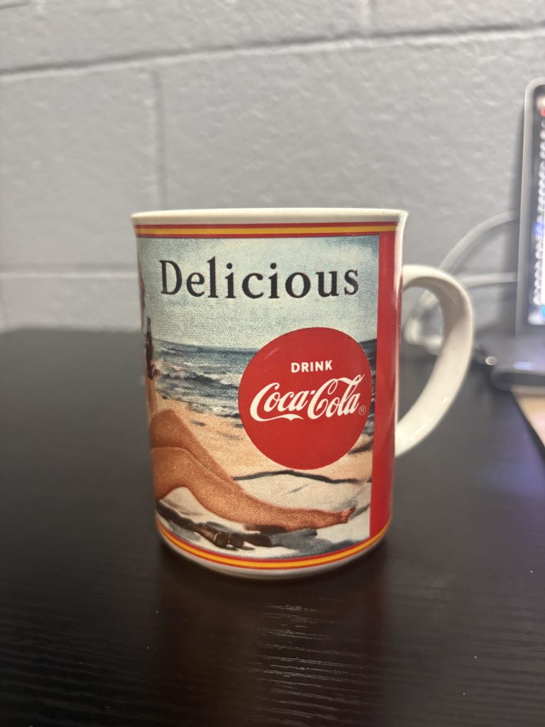 1987 vintage Coca-Cola "Through The Years: 1950" ceramic mug featuring classic pin-up style beach illustration, a nostalgic and highly collectible piece of breweriana for enthusiasts building a high-value portfolio today.