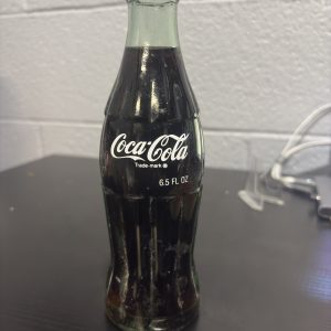 Rare international 6.5 fl oz Coca-Cola glass bottle from Pakistan, featuring unique Urdu script branding, a highly sought-after piece for global soda memorabilia collectors looking to add high-value, authentic assets to their collection today.