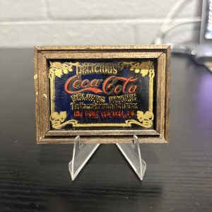 Antique-style framed Coca-Cola "Delicious" miniature glass sign, a sophisticated and rare piece of breweriana decor perfect for collectors looking to add high-value, timeless assets to their portfolio today.