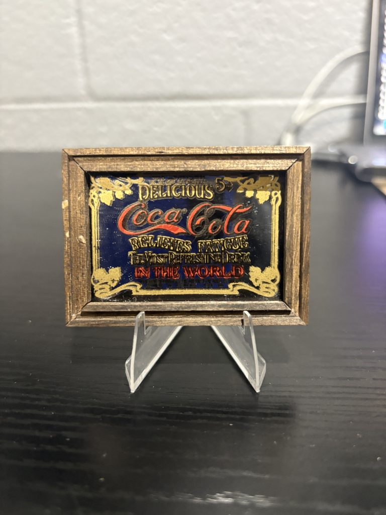 Antique-style framed Coca-Cola "Delicious" miniature glass sign, a sophisticated and rare piece of breweriana decor perfect for collectors looking to add high-value, timeless assets to their portfolio today.