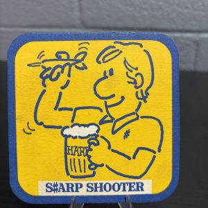 Vintage Harp Lager "S#ARP SHOOTER" beer coaster, a high-vibration collectible featuring a playful illustrated character and branded pattern on the reverse side, perfect for collectors of eccentric breweriana.