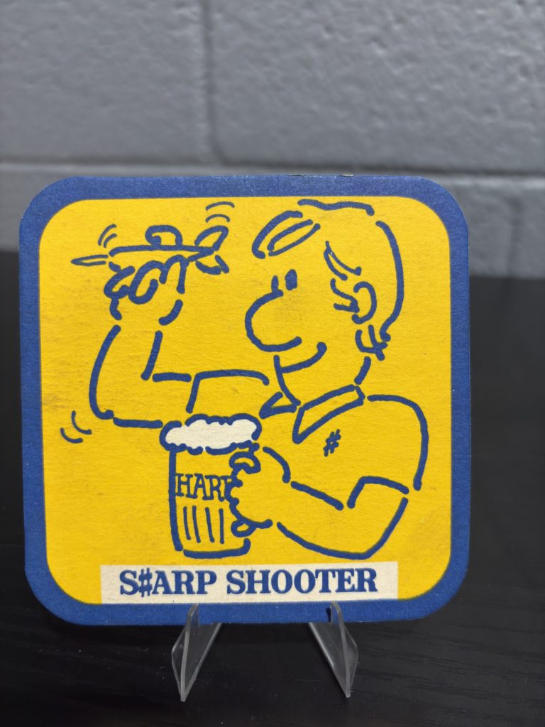 Vintage Harp Lager "S#ARP SHOOTER" beer coaster, a high-vibration collectible featuring a playful illustrated character and branded pattern on the reverse side, perfect for collectors of eccentric breweriana.