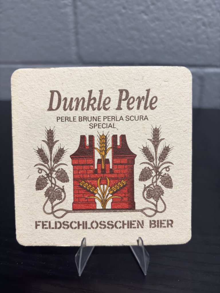 Set of 2 vintage Feldschlösschen Bier coasters, featuring branding for Dunkle Perle and a promotional image depicting a sophisticated dining scene, perfect for collectors looking to manifest prosperity and add authentic