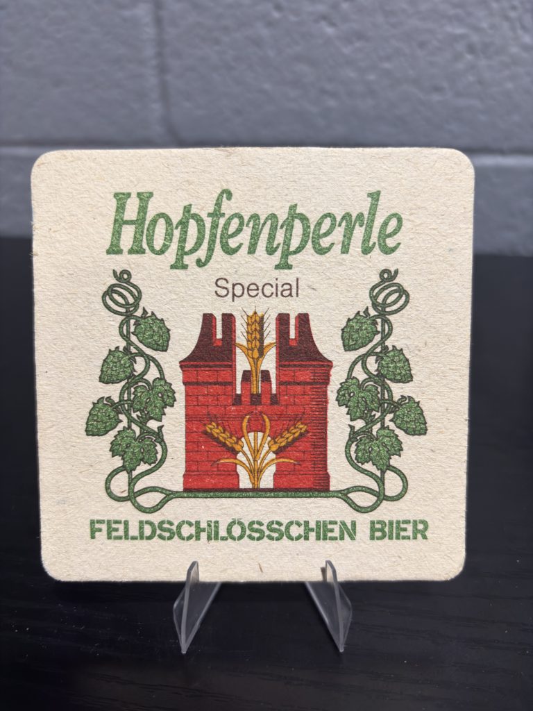 Vintage Feldschlösschen Bier "Hopfenperle" coaster, featuring elegant branding and a promotional image of a waiter, a high-vibration collectible perfect for enthusiasts of international breweriana looking to manifest prosperity and add authentic brand history to their portfolio.