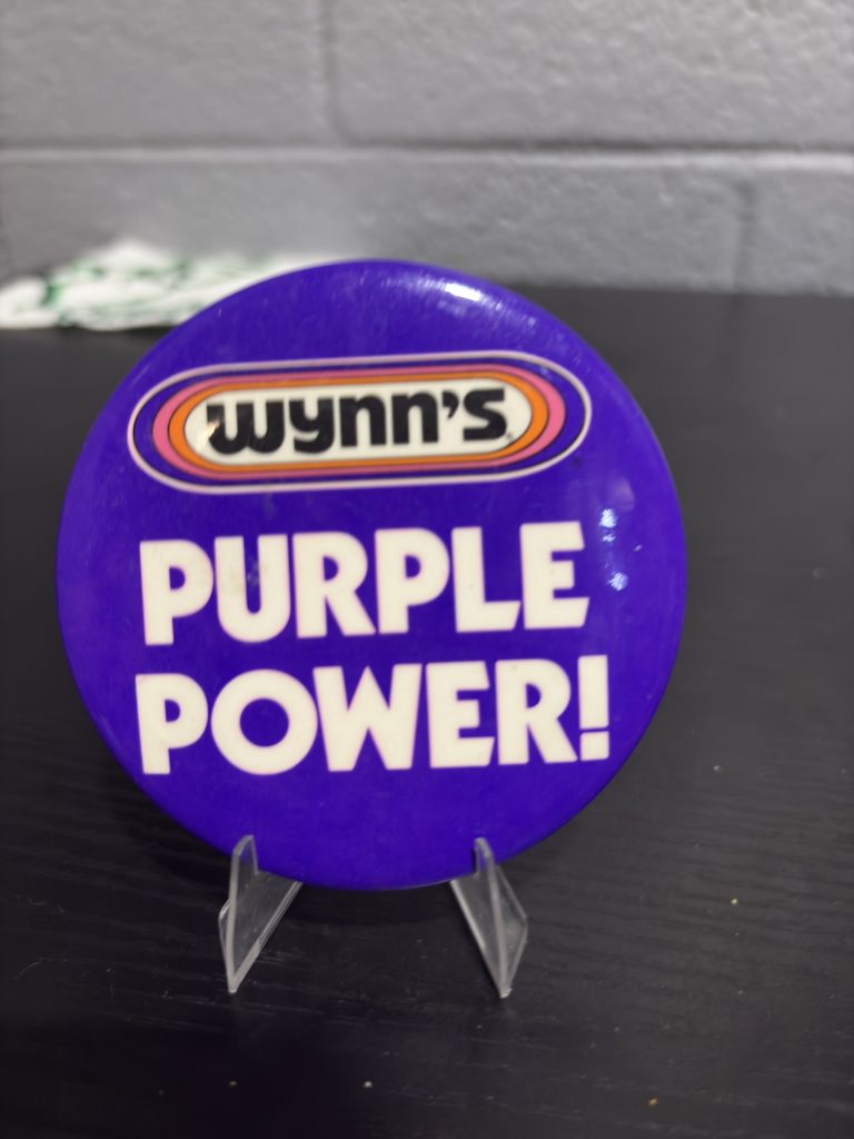 Vintage Wynn's "Purple Power!" promotional pinback button, a high-vibration collectible perfect for enthusiasts of automotive advertising memorabilia looking to manifest prosperity today.