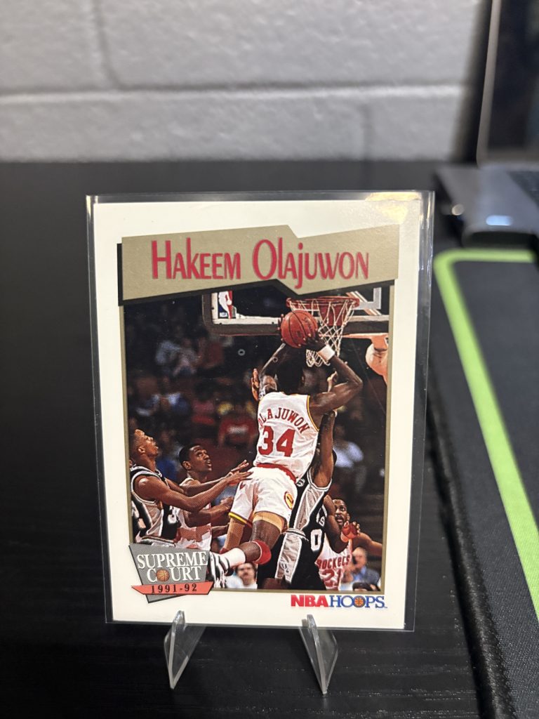 Vintage 1991-92 NBA Hoops "Supreme Court" Hakeem Olajuwon trading card, a master-number 11 frequency collectible for basketball enthusiasts focused on historic excellence and dominant visionary performance on the court.