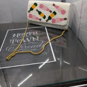 White beaded clutch purse featuring the words Pour More with colorful cocktail designs and a gold chain strap