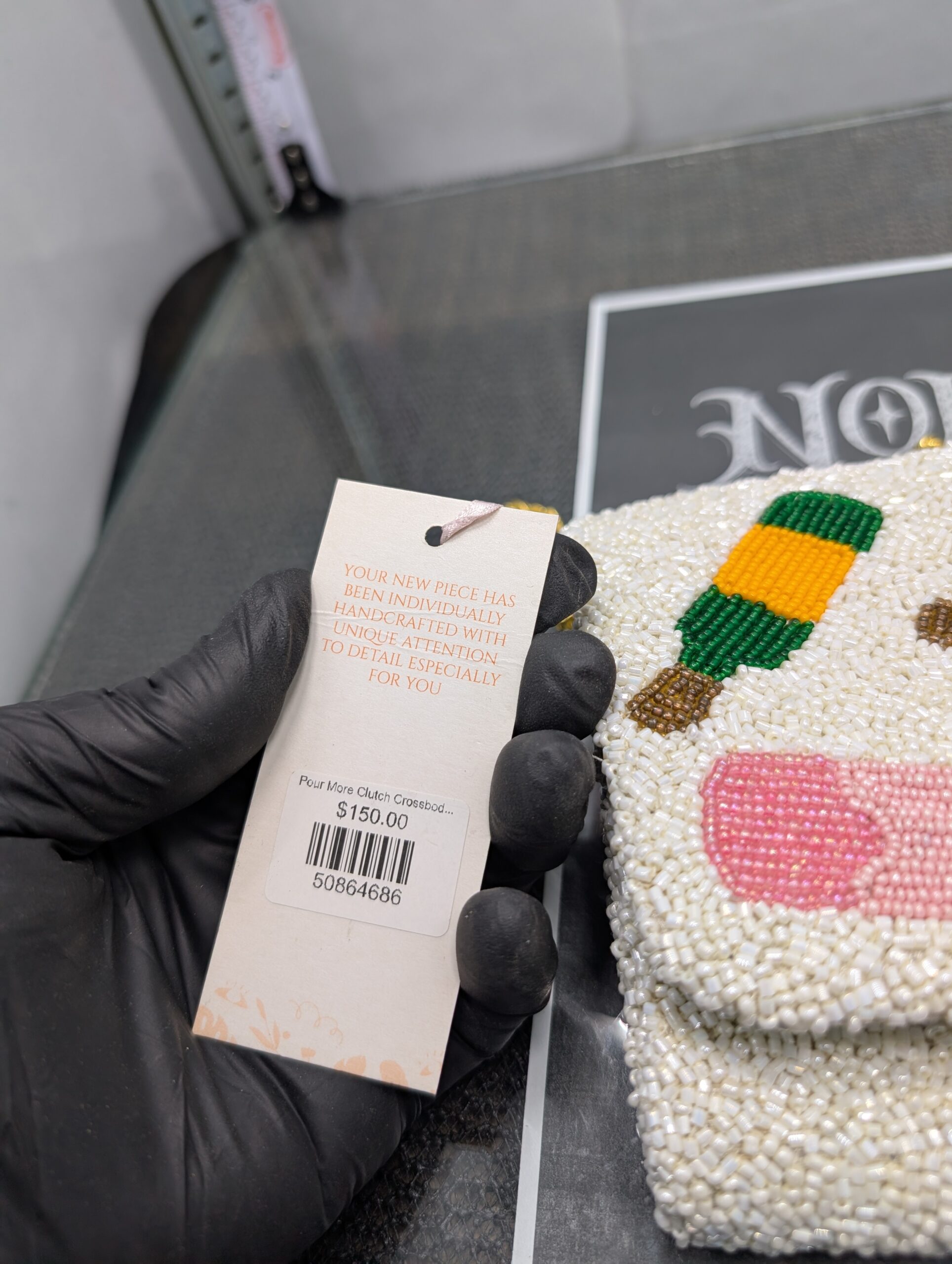 White beaded clutch purse featuring the words Pour More with colorful cocktail designs and a gold chain strap.