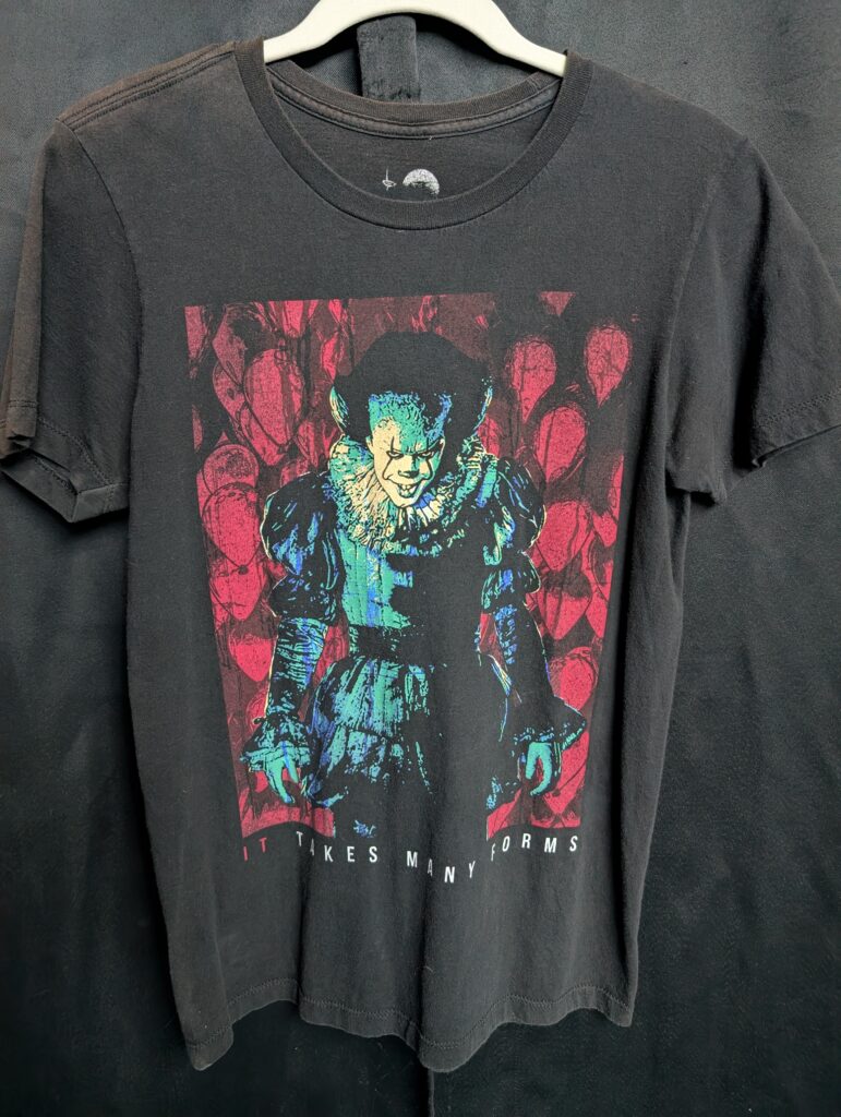 Vintage faded black graphic t-shirt featuring Pennywise from the movie IT with red balloons and the text 'IT TAKES MANY FORMS'.