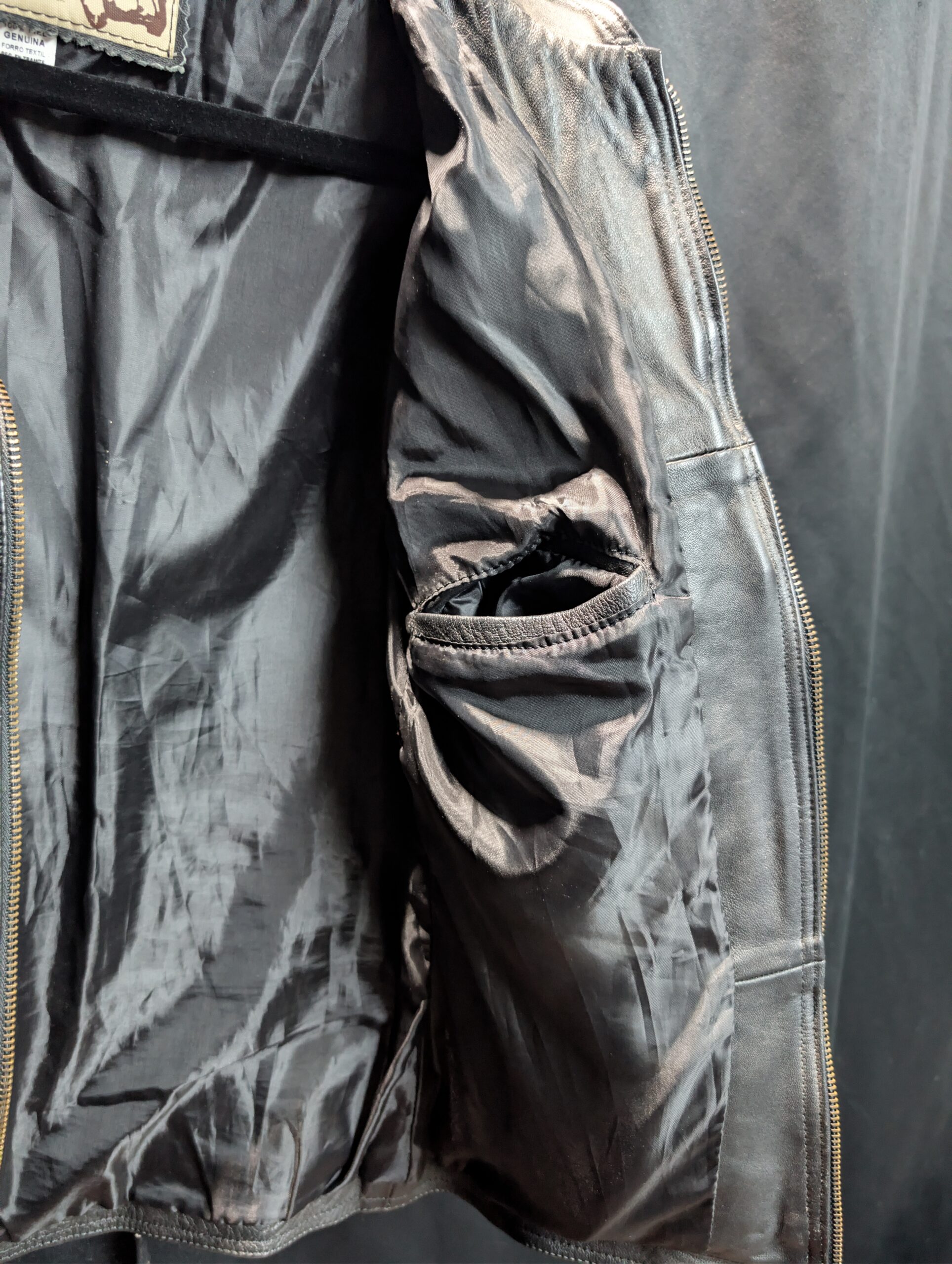 Black genuine sheepskin leather motorcycle jacket by Creaciones Gabriel featuring ribbed shoulder details and brass zipper pockets.