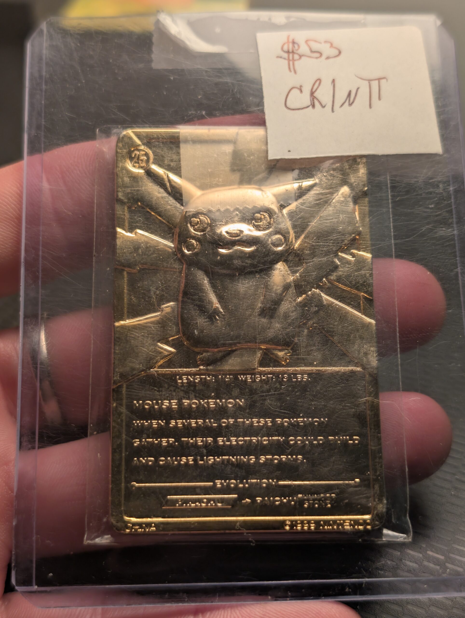 Person holding a vintage 1999 Burger King 23K gold-plated Pikachu Pokémon promotional trading card inside a clear protective case with a small handwritten label.