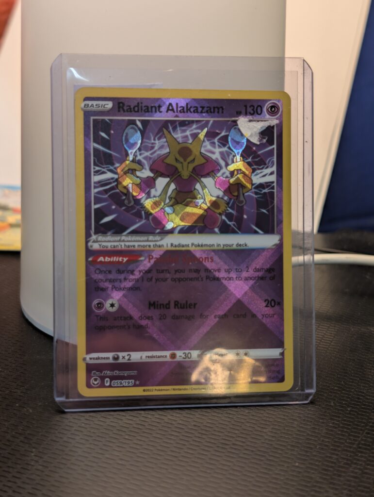 Radiant Alakazam holographic Pokémon trading card, number 059/195 from the Silver Tempest set, displayed in a clear protective plastic sleeve.