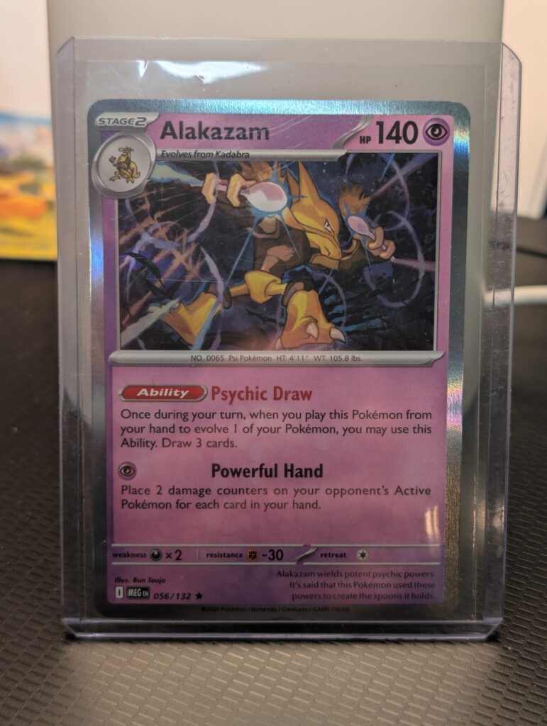 Holographic Alakazam Pokémon trading card, number 056/132 from the Mega Evolution expansion set, displayed in a clear protective plastic sleeve.