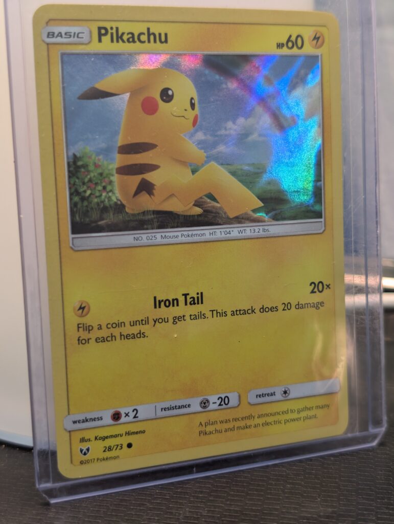 Holographic Pikachu Pokémon trading card, number 28/73 from the 2017 Shining Legends expansion, featuring the exclusive Cosmos holofoil pattern, displayed in a clear protective plastic sleeve.