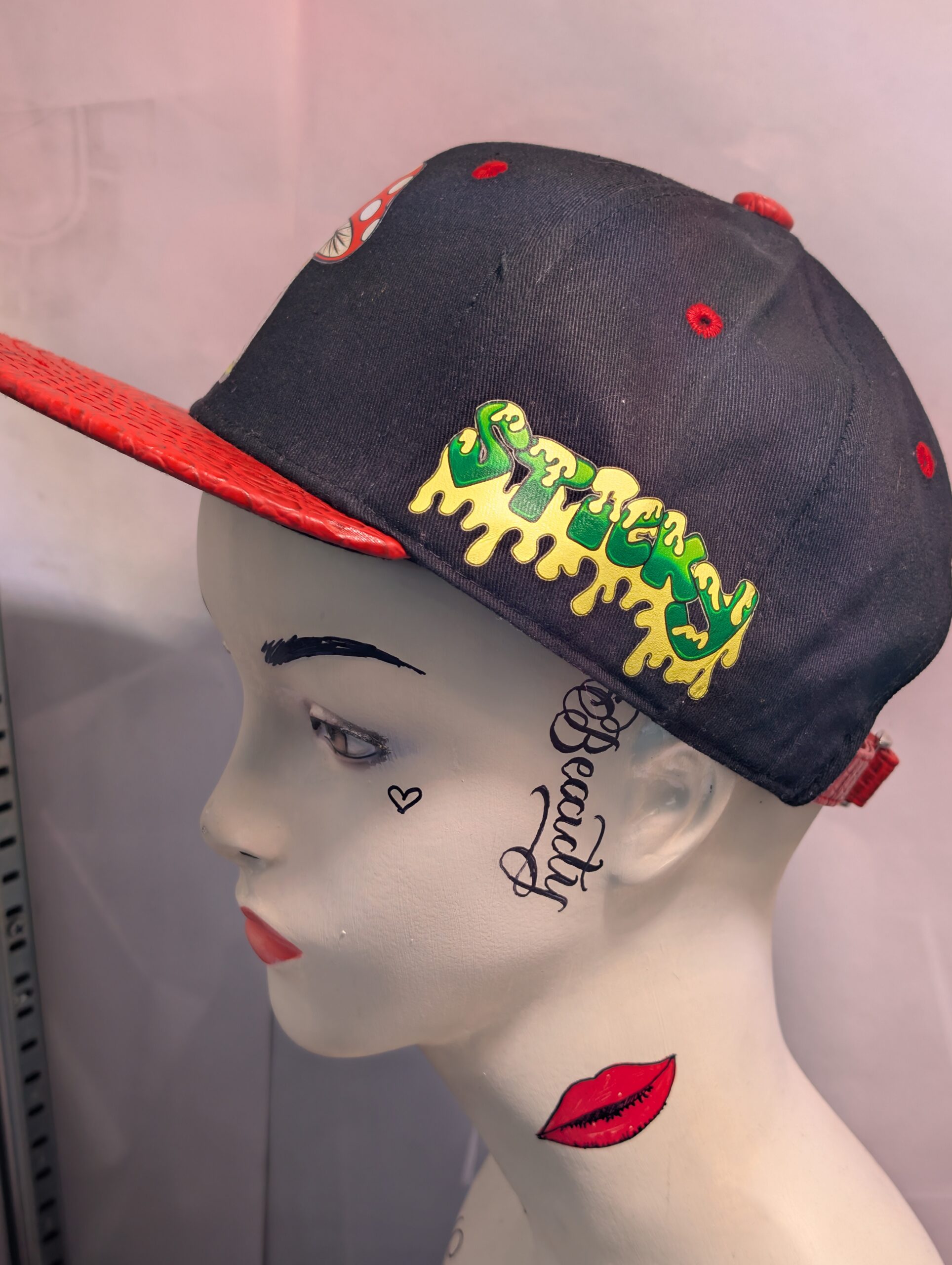 Black structured streetwear snapback hat featuring embroidered cartoon mushroom graphic alongside bright green dripping slime logo and textured red crocodile faux leather flat bill edge for style.
