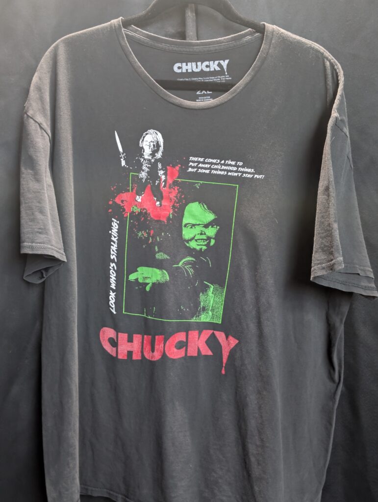 Authentic size two extra large black short sleeve graphic shirt featuring classic Chucky horror movie character holding a knife with green and red vintage distressed print details.