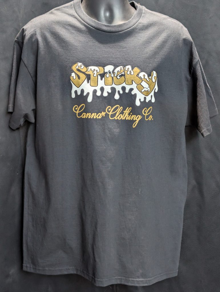 Black shirt featuring gold Sticky Canna drip logo.
