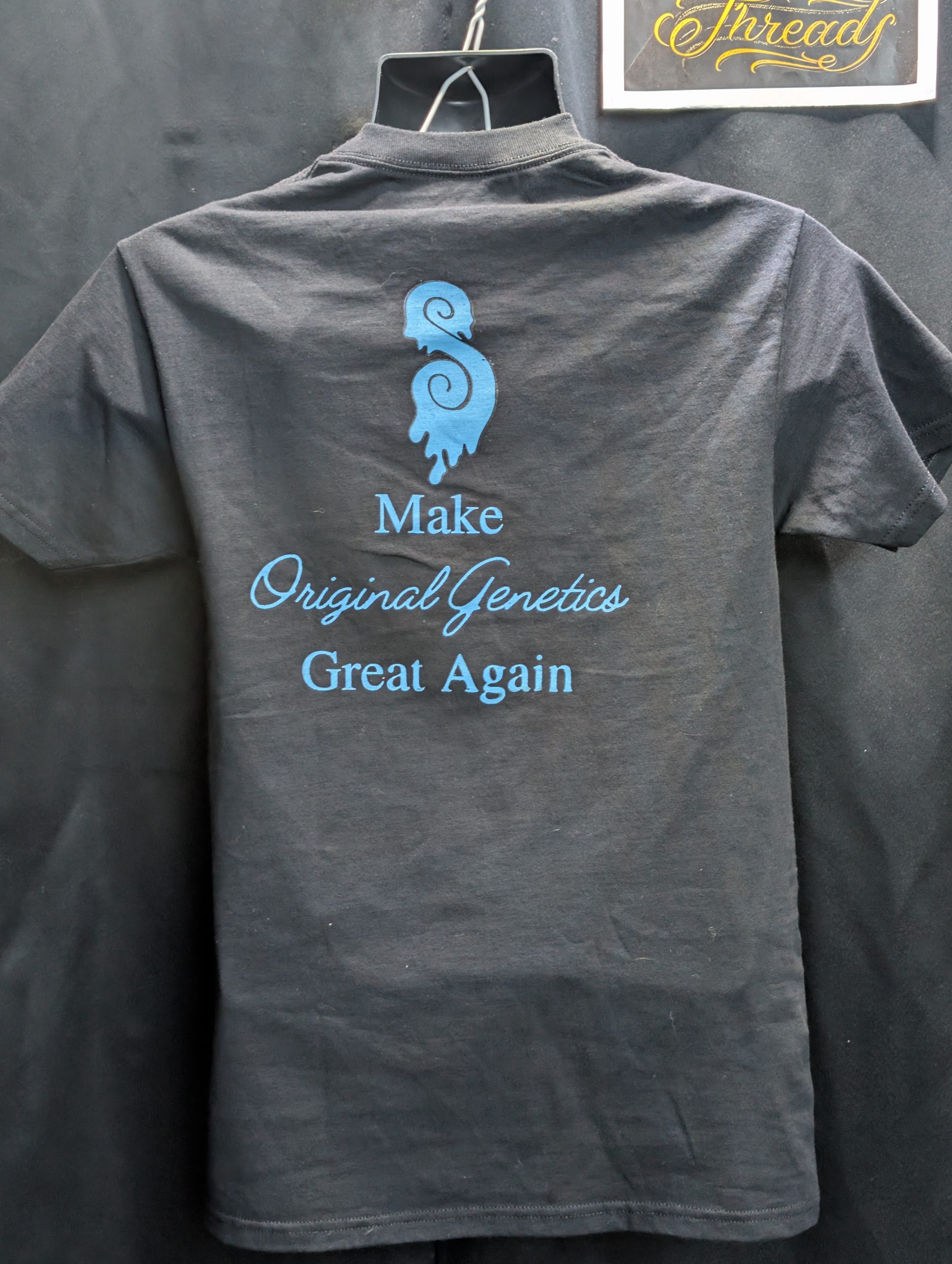 Black shirt featuring blue yellow Sticky Canna logo.