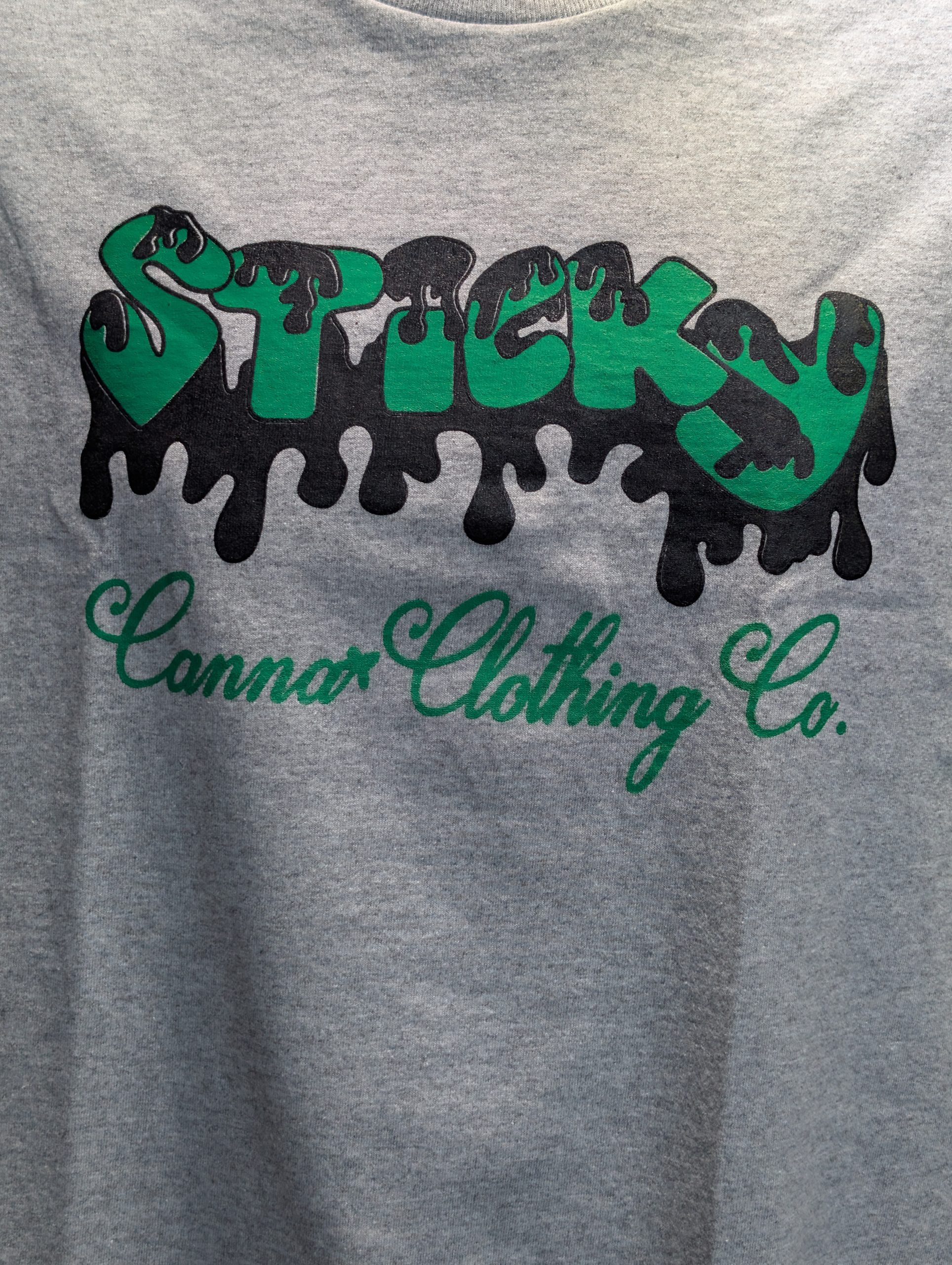 Grey shirt featuring green black Sticky Canna logo.