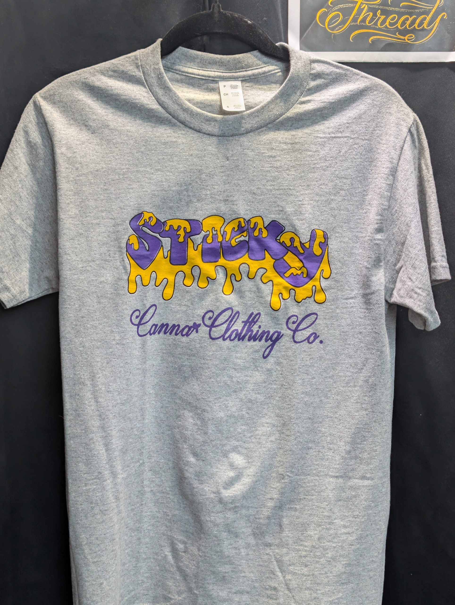 Grey shirt featuring purple yellow Sticky Canna logo.