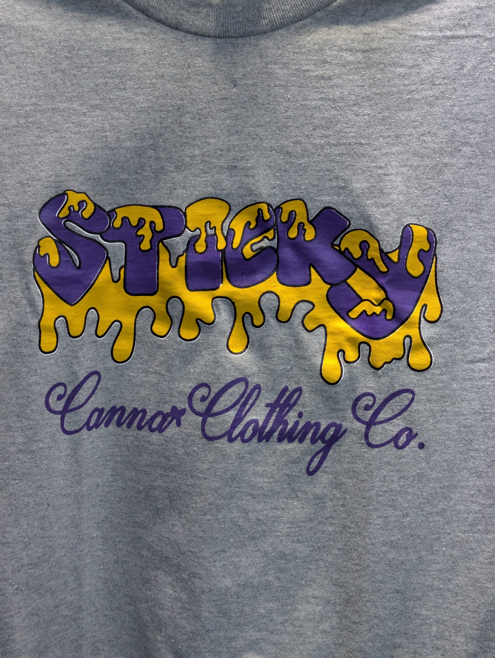 Grey shirt featuring purple yellow Sticky Canna logo.