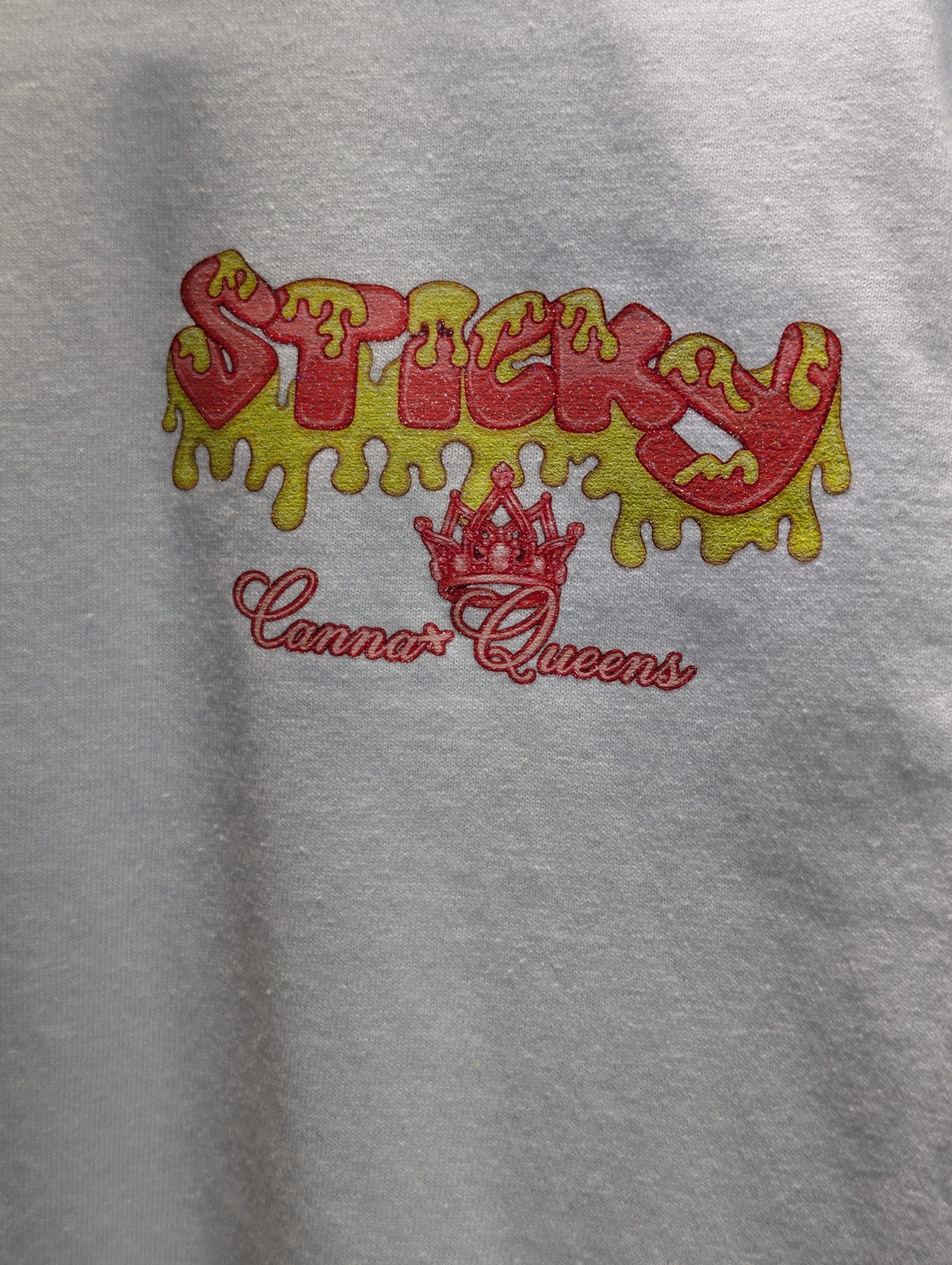 White shirt featuring red yellow Sticky Queens logo.