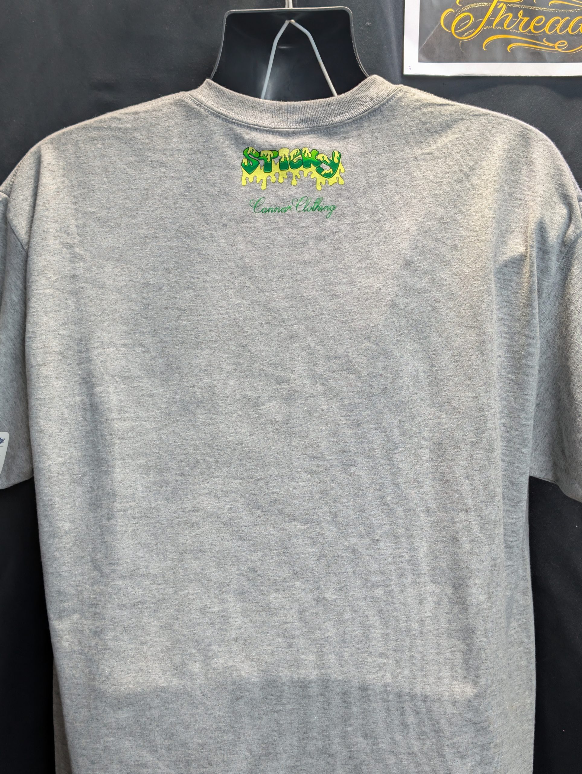 Grey shirt featuring blue wave Sticky Canna logo.