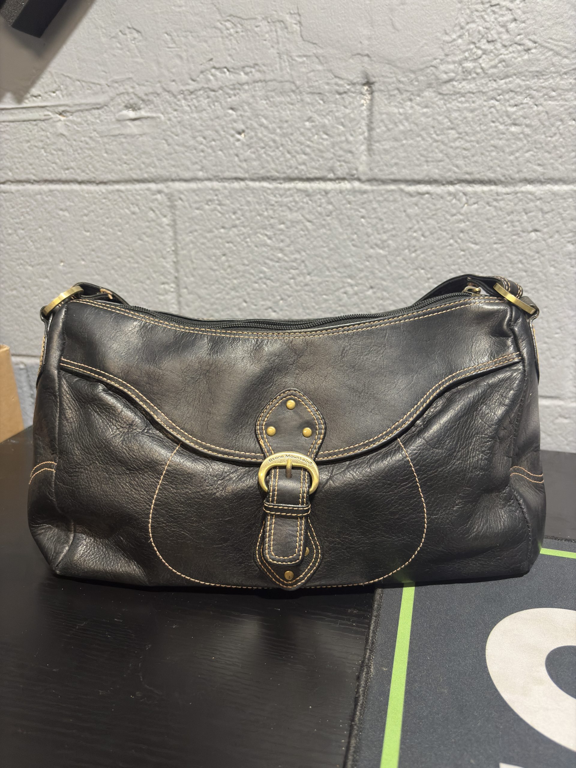 Vintage black leather Stone Mountain shoulder bag with contrast stitching and gold buckle detail