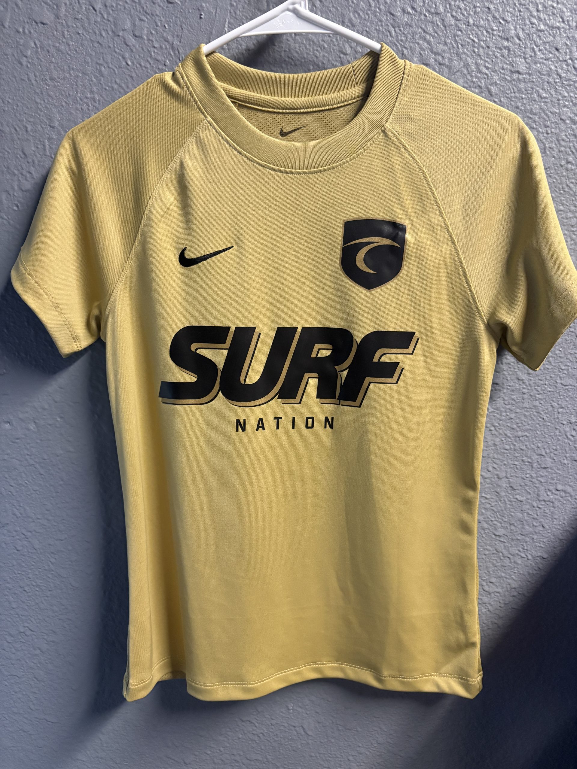 Nike Dri-FIT gold performance athletic shirt with "Surf Nation" branding and logo crest, size XS.
