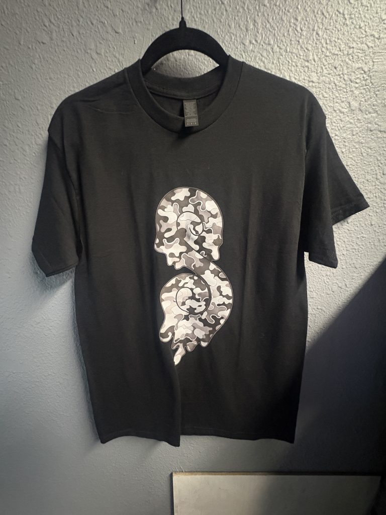 Black t-shirt with grey camo-pattern swirl logo on the front and small "Sticky" logo on the back neck, size M.