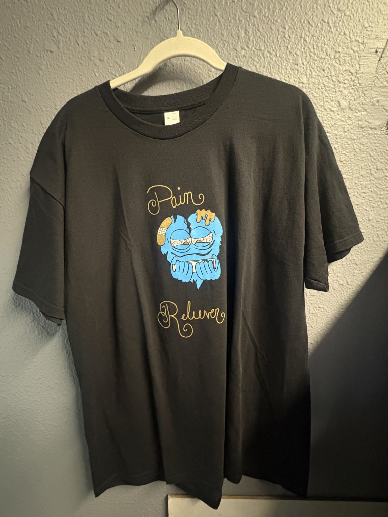 Black graphic t-shirt with "Pain Reliever" character design on front and blue swirl art on back, size XL.