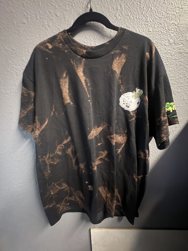 Acid-wash black t-shirt with "Embrace Your Veggies" graphic on front and astronaut "Planetary Sessions" print on back.