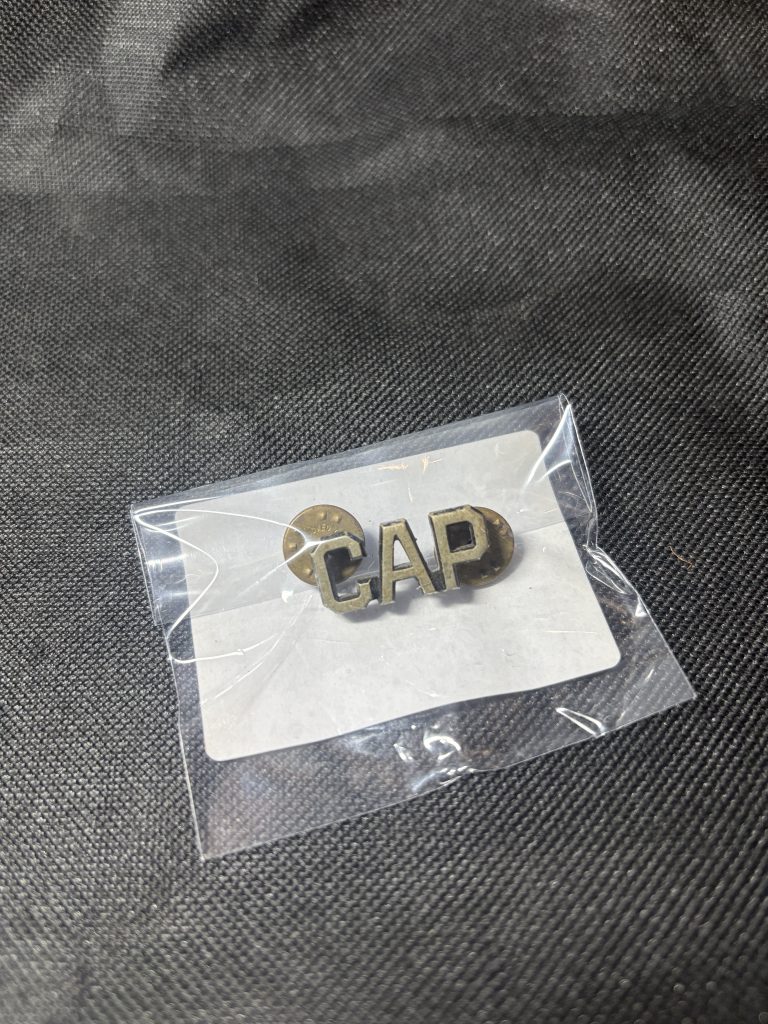 Vintage Civil Air Patrol "CAP" metal insignia pin in a protective sleeve.