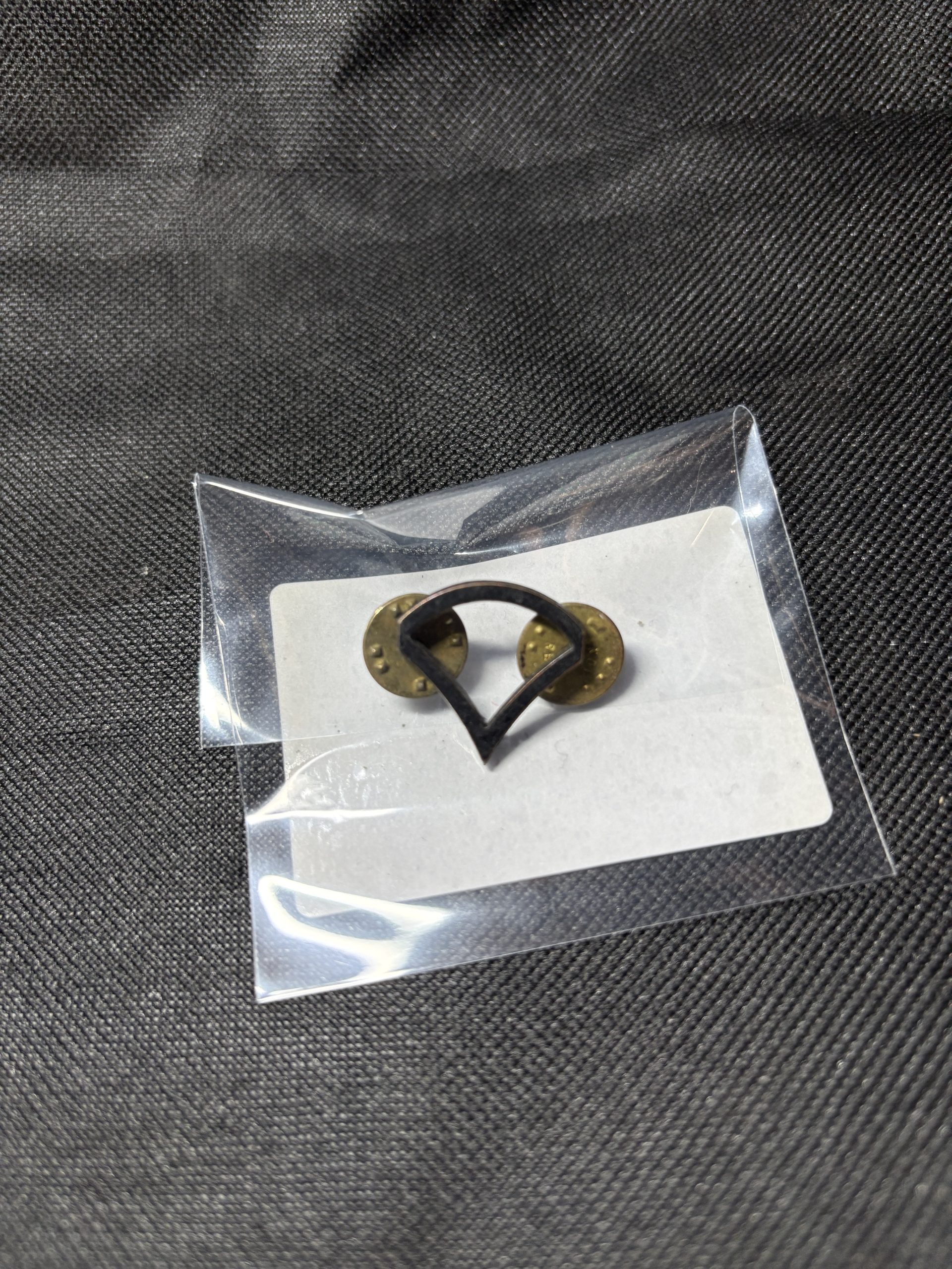 Vintage U.S. Army Private First Class (PFC) rank insignia pin in a protective sleeve.