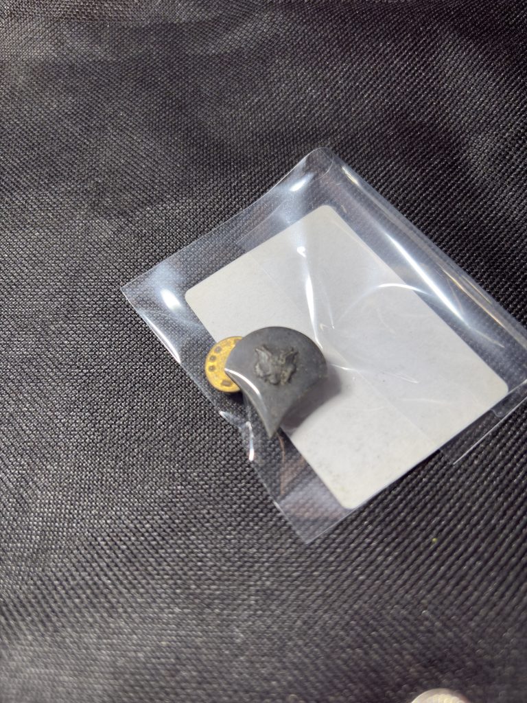 Vintage U.S. Army Private (PVT) rank insignia pin in a protective sleeve.
