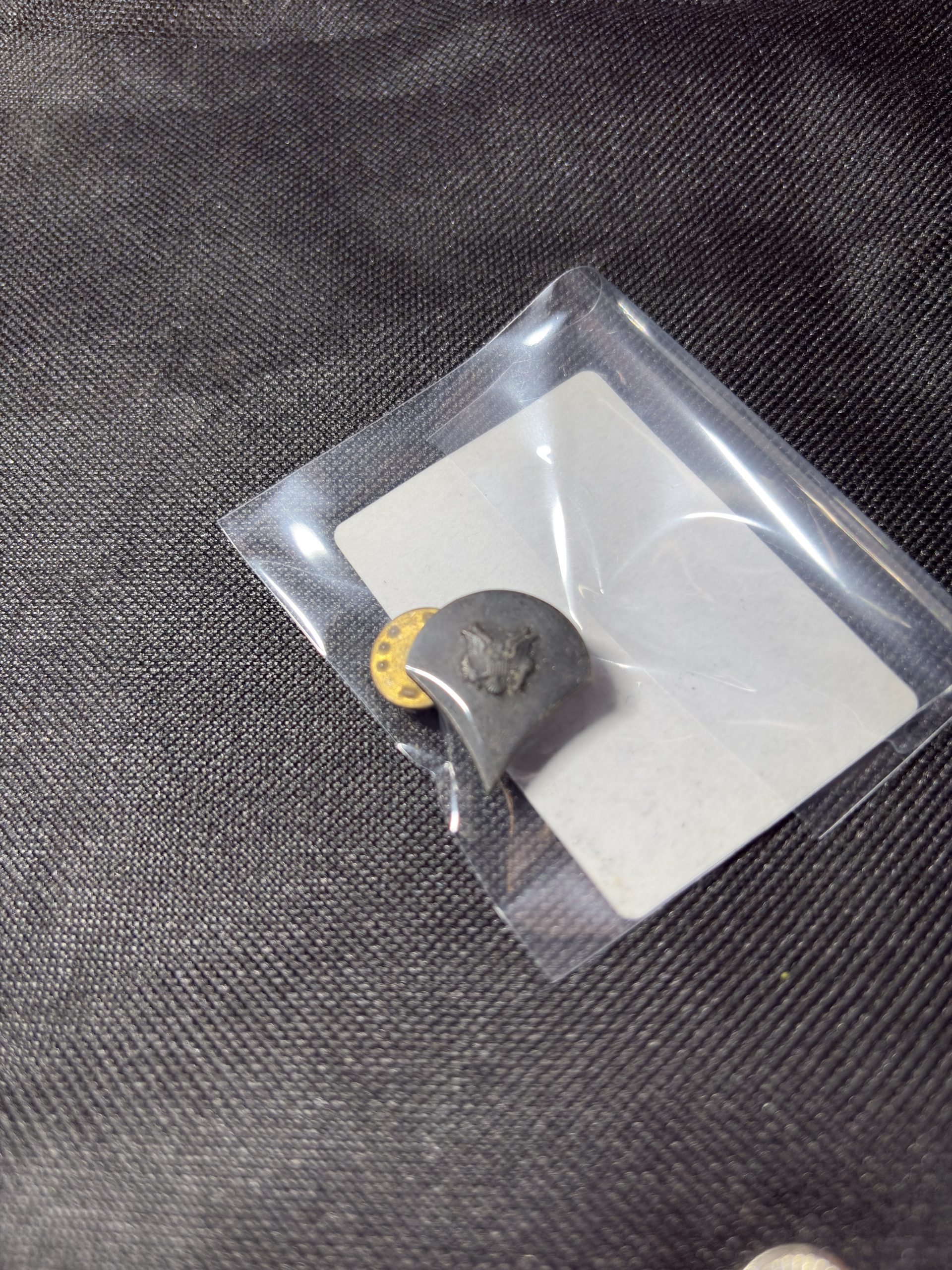 Vintage U.S. Army Private (PVT) rank insignia pin in a protective sleeve.
