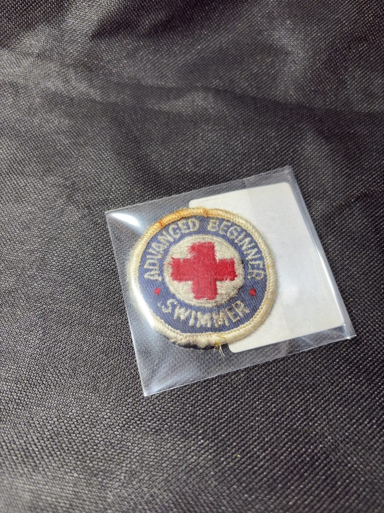 Vintage American Red Cross Advanced Beginner Swimmer embroidered patch in a protective sleeve.