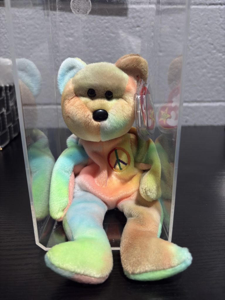 Ty Beanie Baby Peace tie-dye bear with peace sign emblem in a clear display case.