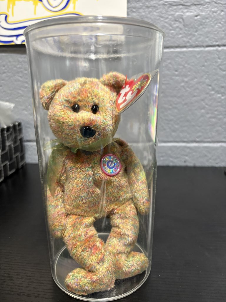 Ty Beanie Baby Speckles tie-dye bear with chest emblem in a clear display cylinder.
