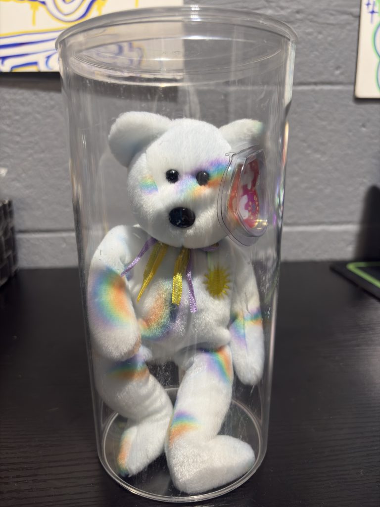 Ty Beanie Baby Cheery rainbow stripe bear with sun chest emblem in a clear display cylinder.