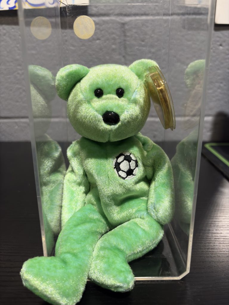 Ty Beanie Baby Kicks lime green soccer bear with chest emblem in a clear display case.