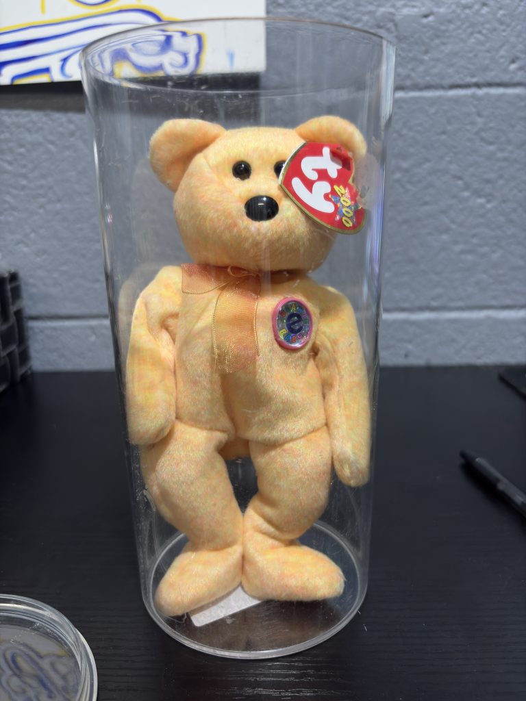 Ty Beanie Baby Sunny yellow tie-dye bear with chest emblem in a clear display cylinder.