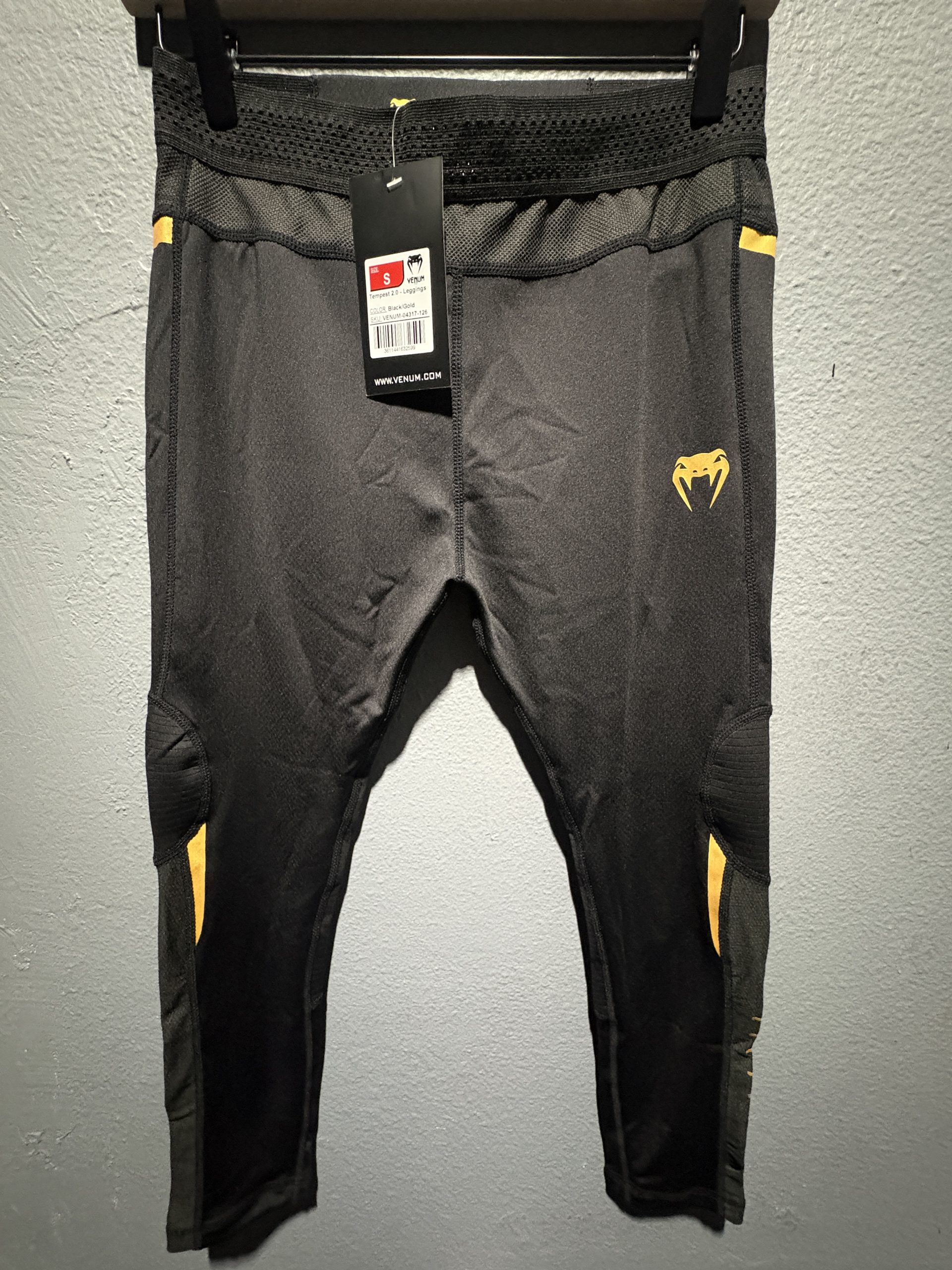 Venum Tempest 2.0 Leggings in Black and Gold showing the waistband tag, gold logo, and compression fit in size S.