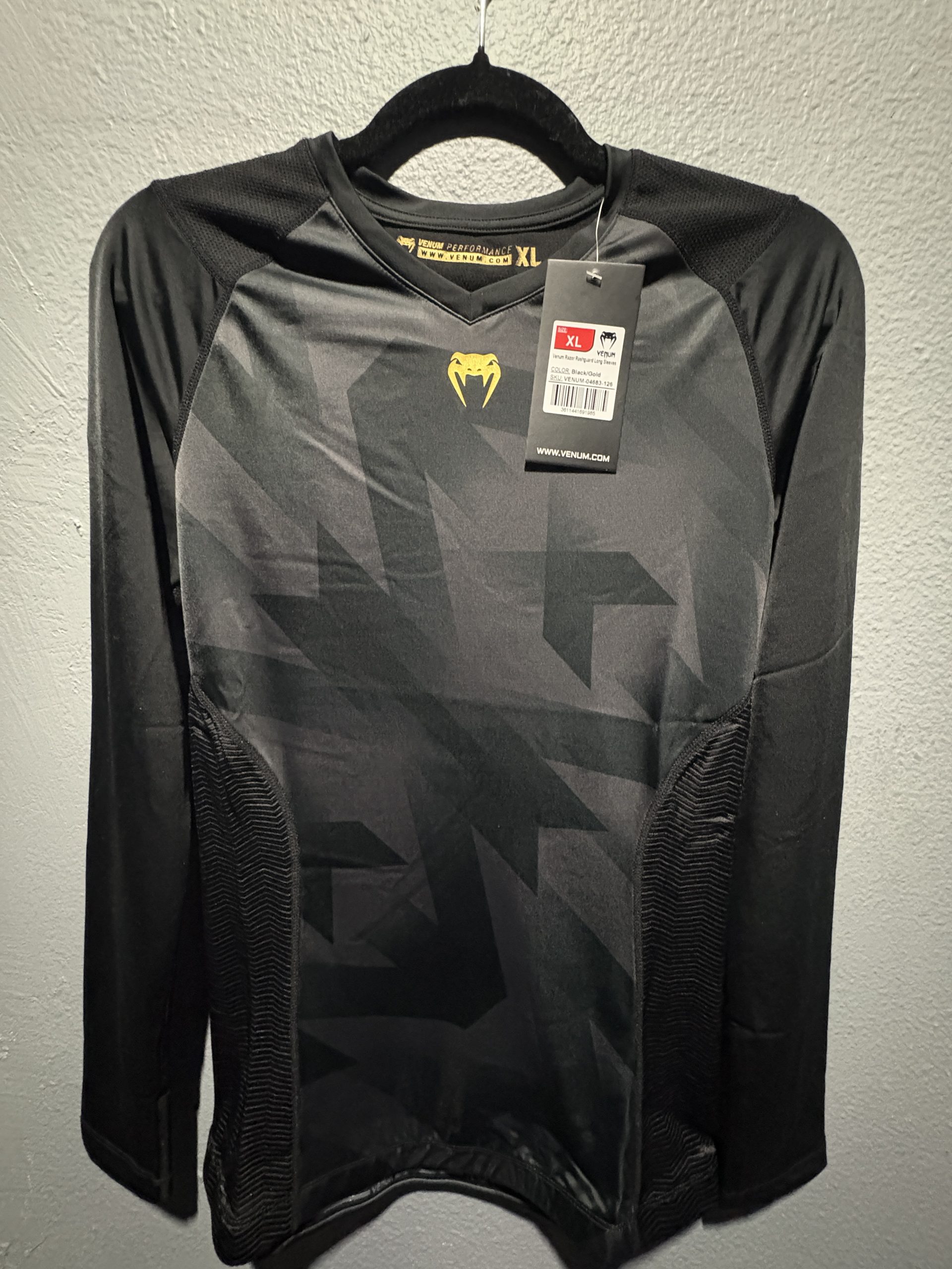 Venum Razor Long Sleeve Rashguard in Black and Gold showing the chest logo, tag, and V-neck collar in size XL.